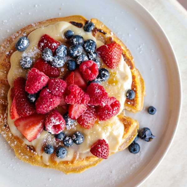 Leo & Lily pancakes topped with cream, fresh raspberries, strawberries, blueberries, and powdered sugar.