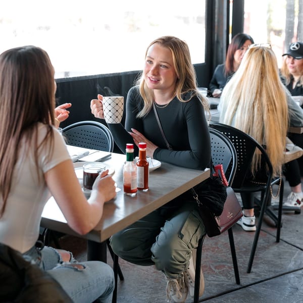 Two women enjoying coffee and conversation at a table in Leo & Lily restaurant.